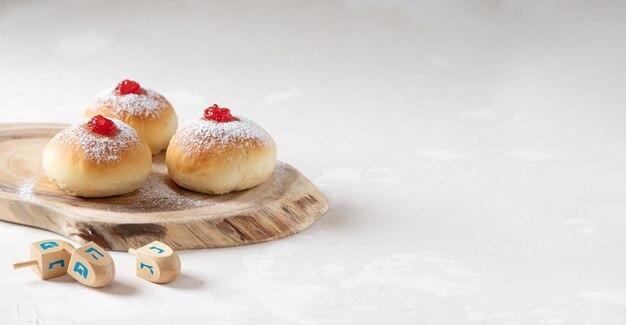 Hanukkah donutsand traditional spinning dreidel on a wooden board.  Close up