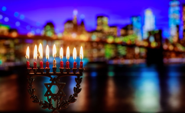 Hanukkah menorah symbol of Jewish traditional holiday Brooklyn Bridge over night New York City with lights