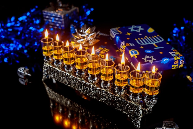 Hanukkah menorah with burning oil candles and gift boxes. Jewish holiday.