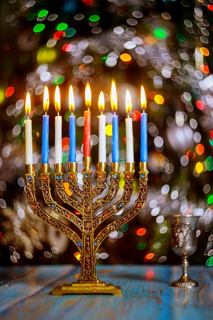 Hanukkah table with menorah and burning candles on sparkle surface with blurred colored lights