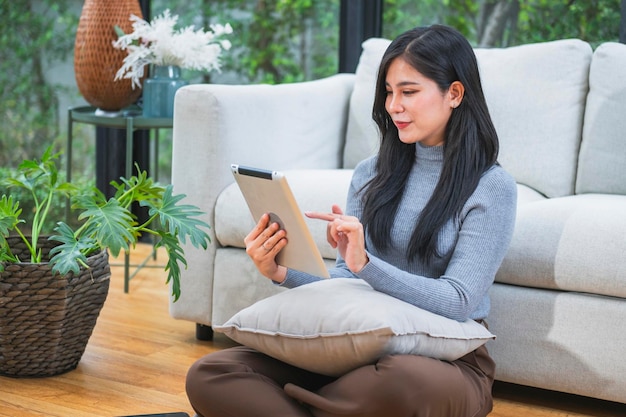 写真 幸せにリラックスした若い女性が携帯電話を使ってソファーに座っています