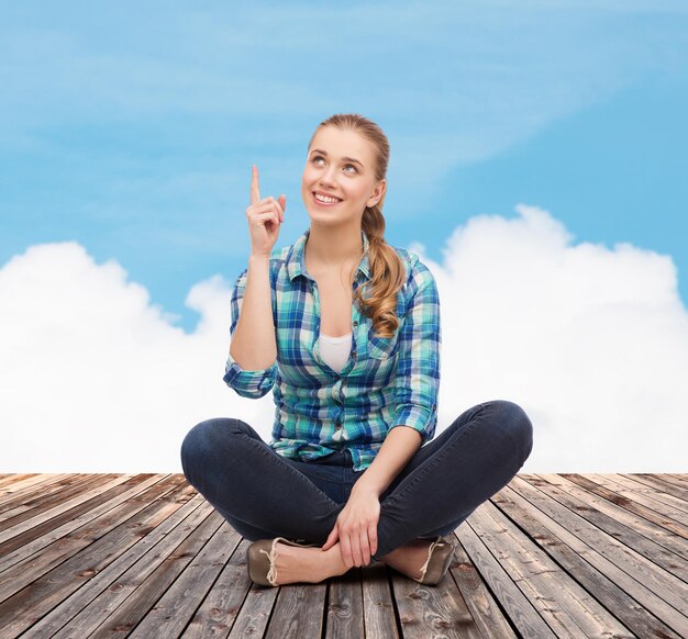 happiness, advertising and people concept - smiling young woman pointing finger up