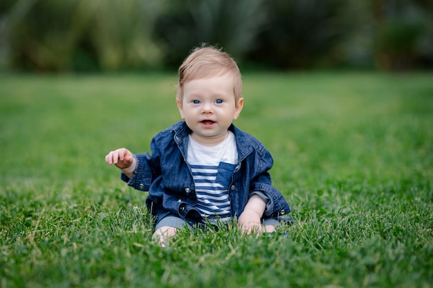 写真 幸福フィールドの芝生に座っている男の子春または夏の公園に座っている男の子