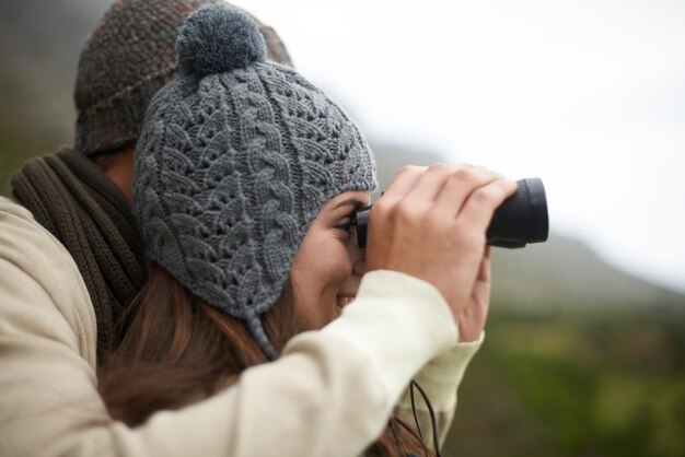 Photo happiness binocular and face of hiking couple looking at outdoor view of nature journey travel adventure or active walk profile trekking and people explore destination bird watching or wellness