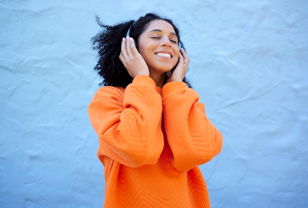 Happiness black woman and headphones for streaming music and cheerful on blue studio background African American female lady or headset for audio sounds and podcast with girl smile and backdrop