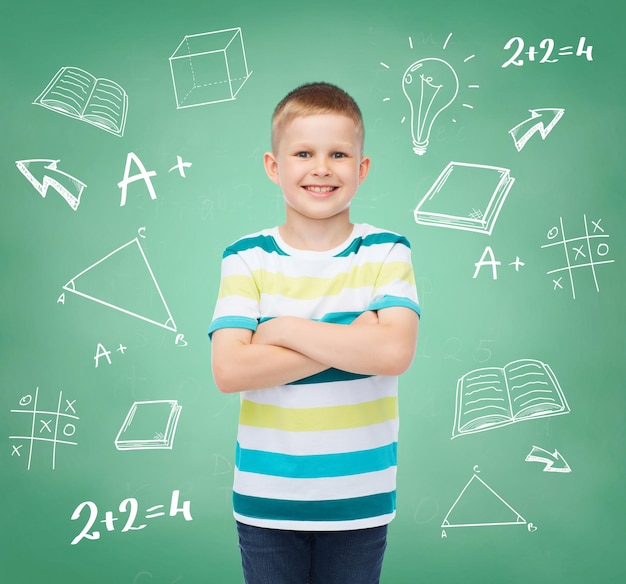 happiness, childhood, school, education and people concept - smiling little boy over green board with doodles background