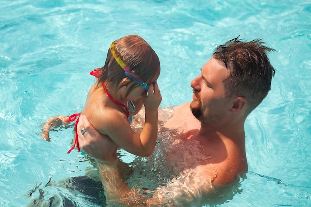 Happiness of daddy and little girl daughter playing fun in swimming pool
