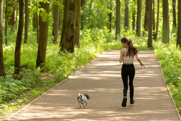 幸福、感情、家族の価値観の概念。女の子は犬と一緒に走り、楽しんで、遊びます