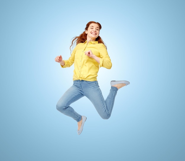 happiness, freedom, motion and people concept - smiling young woman jumping in air over blue background