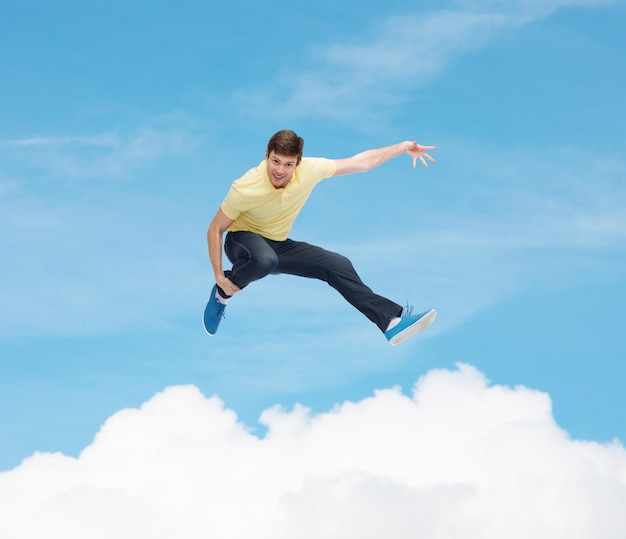 행복, 자유, 운동 및 사람 개념 - 흰 구름 배경으로 푸른 하늘 위로 점프하는 웃고 있는 청년