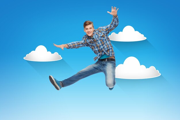 happiness, freedom, movement and people concept - smiling young man jumping in air over blue sky with white clouds background