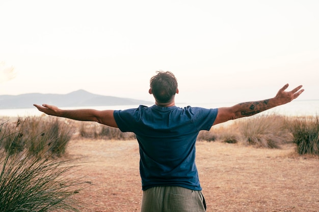 Happiness and freedom travel people lifestyle One man back view outstretching arms overjoy and excited admiring amazing journey adventure destination in background with ocean and island Joyful life