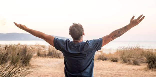 Photo happiness and freedom travel people lifestyle one man back view outstretching arms overjoy and excited admiring amazing journey adventure destination in background with ocean and island joyful life