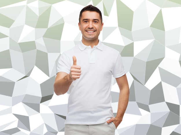 happiness, gesture and people concept - smiling man showing thumbs up over gray graphic low poly background