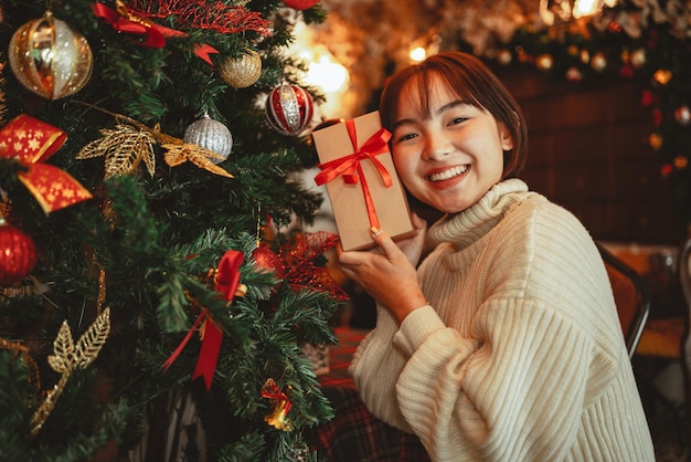 幸せの女の子は、家のお祝いのコンセプトでクリスマスギフトボックスを保持します。