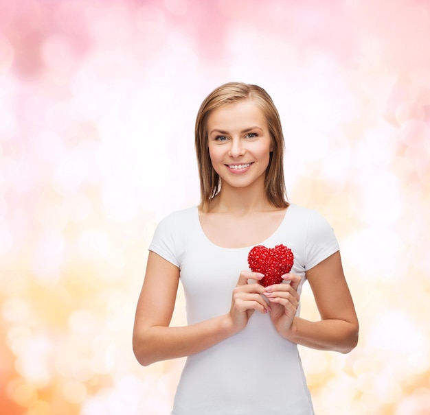 happiness, health and love concept - smiling woman in white t-shirt with heart