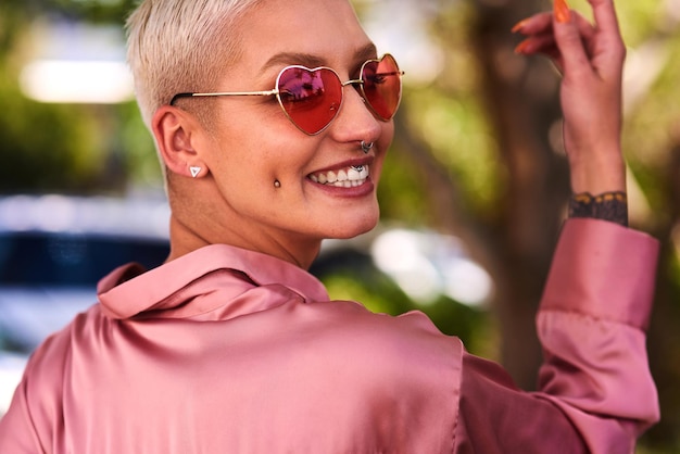 Happiness looks good on anyone Closeup portrait of an attractive and stylish young woman wearing sunglasses relaxing in a park outdoors