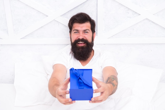 Happiness Make surprise concept Gift for spouse Cute and romantic gift Bearded hipster prepare lovely gift Valentines day gift Spread love Present for sweetheart Happy man relaxing in bed