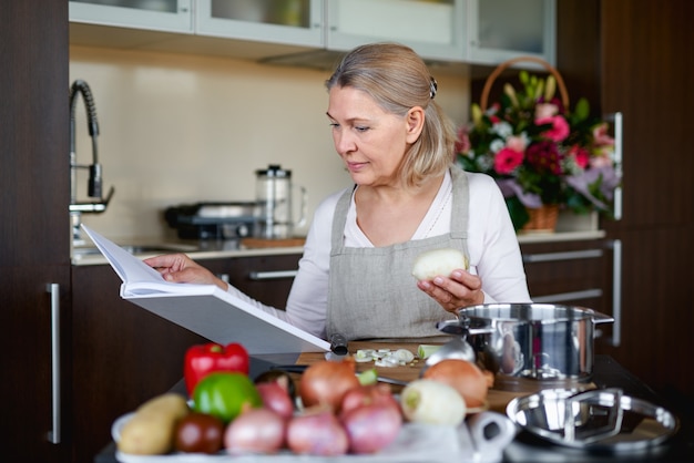 Photo happiness old woman chooses recipe for pie for whole family