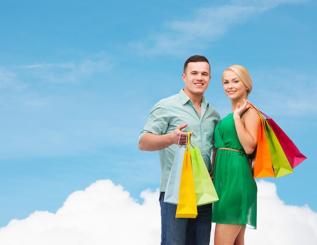 концепция счастья, покупок и пары - улыбающаяся пара с сумками для покупок