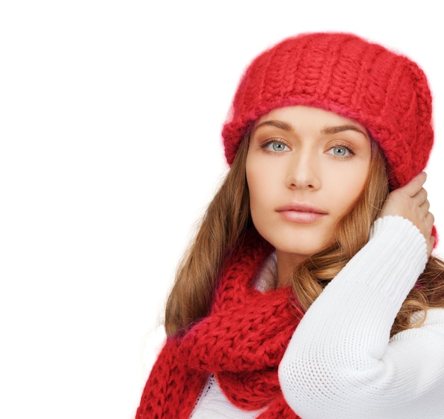 happiness, winter holidays, christmas and people concept - young woman in red hat and scarf over white background