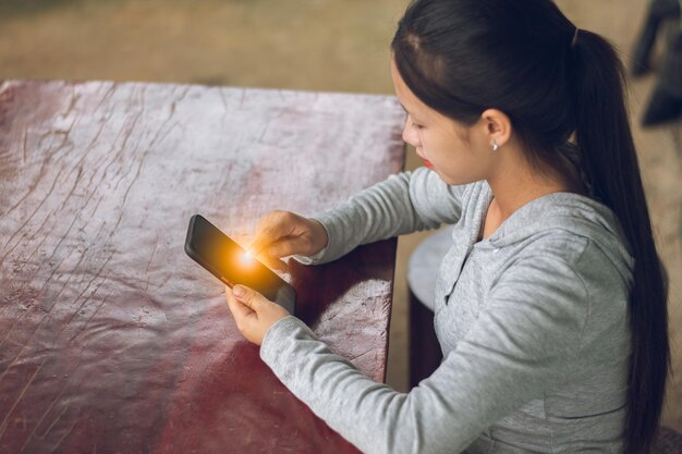 Photo a happiness woman sit down on the desk and holding smartphone with empty screen internet online communication and social media concept copy space for individual text