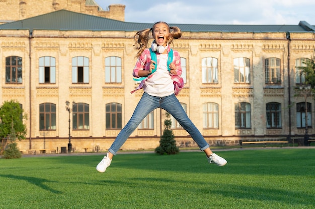 Happy active teenage girl jumping in school yard outdoors September 1