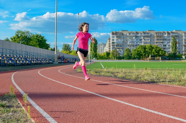 Felice donna attiva jogging in pista, correre e allenarsi su stadio, sport e fitness