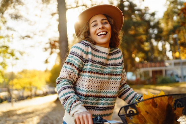 Happy active young woman on bike in autumn park at sunset Concept of people active lifestyle