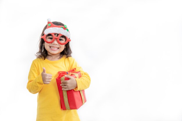 Happy adorable Asian child girl with Christmas gift in hands on white background