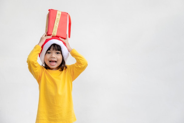 白い背景の上の手でクリスマスプレゼントと幸せな愛らしいアジアの子供の女の子