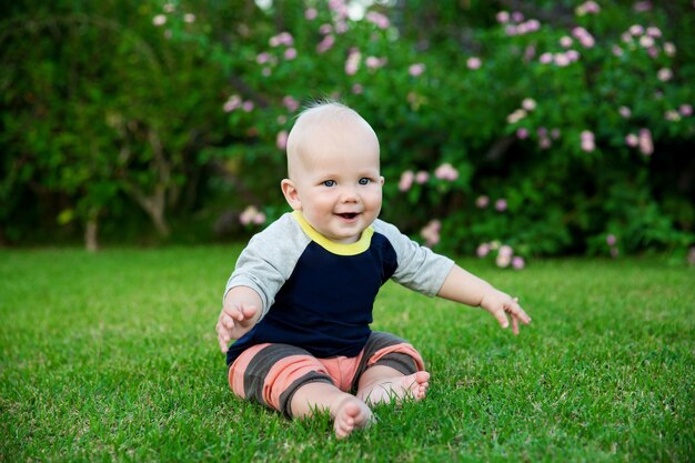 Happy adorable baby boy sitting on the grass