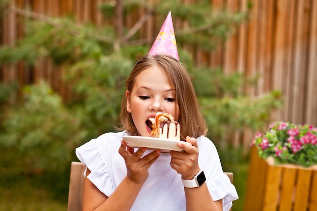 Happy adorable girl eating birthday cake in cafe terrace. 10 year old celebrate birthday.