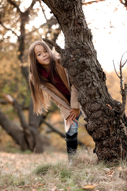 Happy adorable little girl playing with autumn fallen leaves