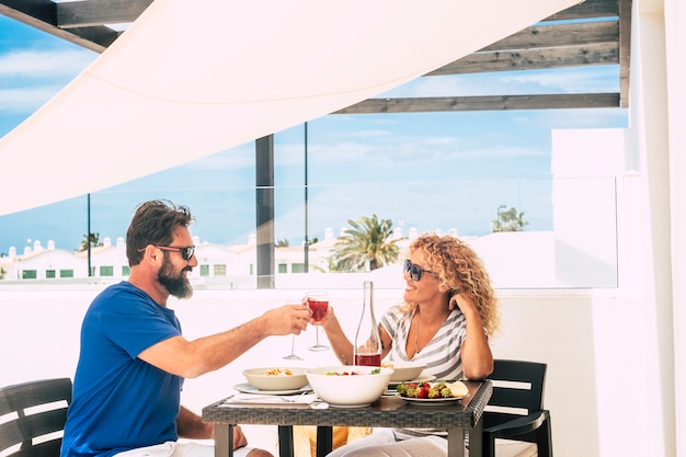 Happy adult caucasian couple in love eating together outdoor on the terrace at home or hotel 