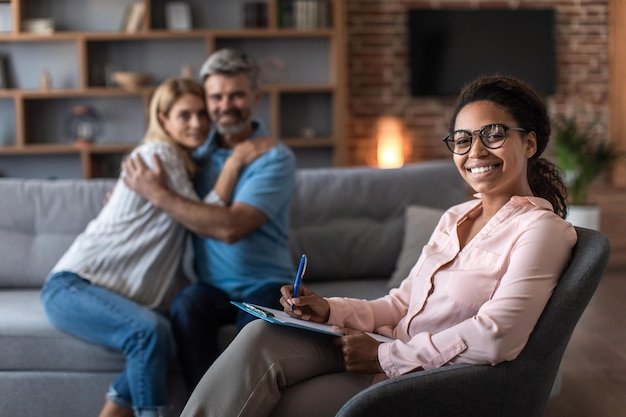 Happy adult caucasian husband hug wife at meeting with psychologist in office clinic interior