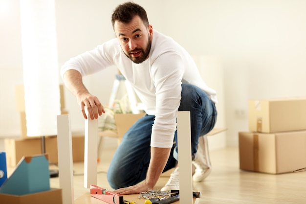 happy adult couple trying to assemble furniture