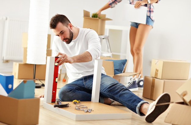 happy adult couple trying to assemble furniture