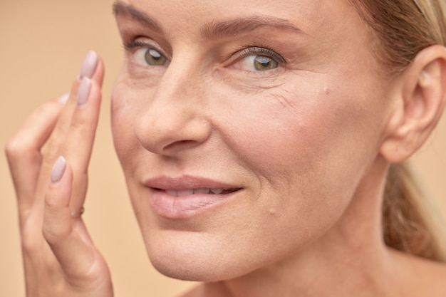 Happy adult lady taking care of the health of her skin