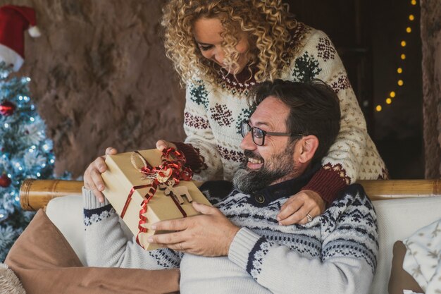 Happy adult people enjoy chrismtas gift exchange at home