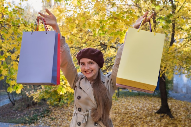 Felice donna adulta con borse della spesa in autunno parco sfondo vendita fall