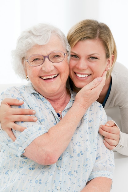 Happy affectionate senior woman embrace her granddaughter at home