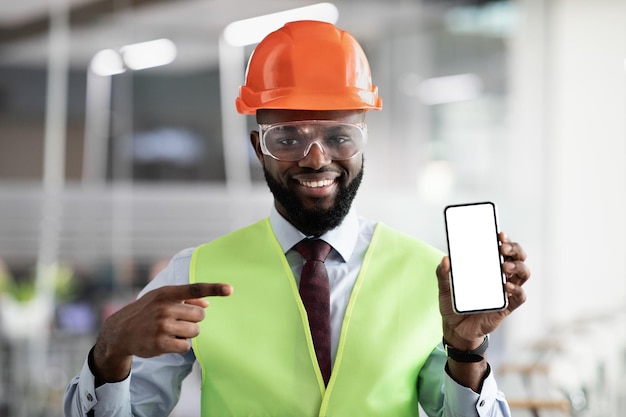 Happy african american architect pointing at smartphone with empty screen