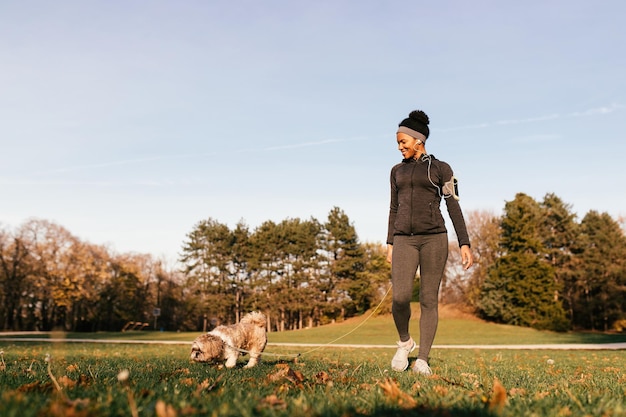 자연 속에서 그녀의 개를 산책하는 동안 즐기는 행복한 아프리카계 미국인 운동 여성