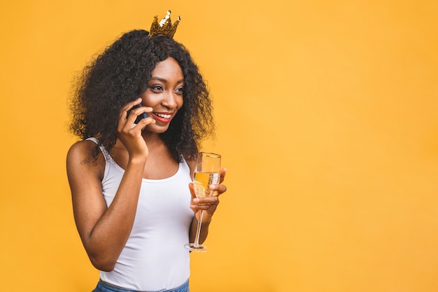 Happy African-American black woman with glass of champagne and golden crown