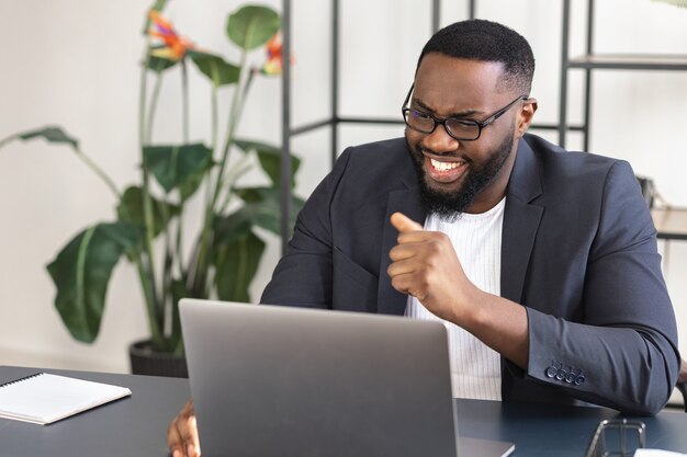 Happy African American businessman having video call sitting at the workplace in the office