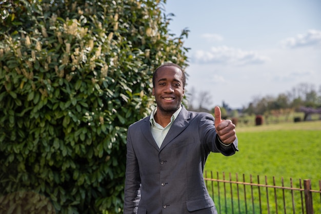 Happy african american businessman makes a thump up gesture outdoor.