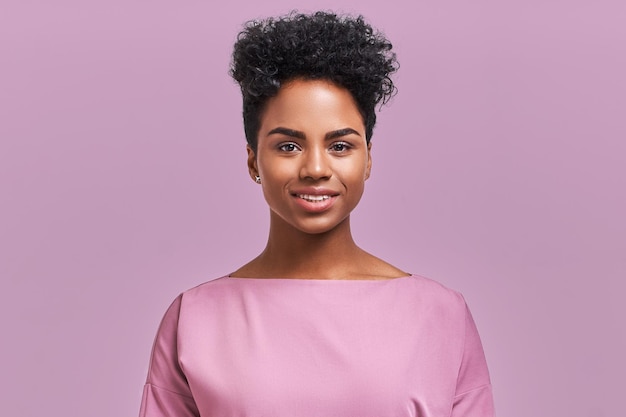 Photo happy african american businesswoman with positive smile, has crisp dark hair, rejoices having weekend and good rest after hard working exhausting week, isolated on lavender wall