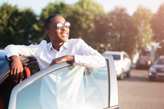 Happy african american next to a car in the summer