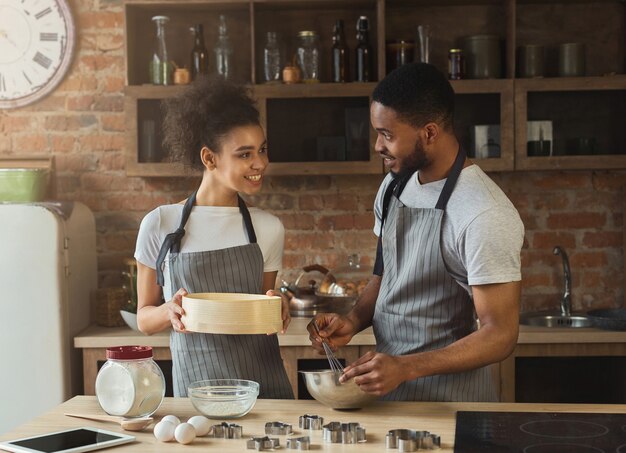 Happy african-american couple cooking cookies together. Family preparing pastry